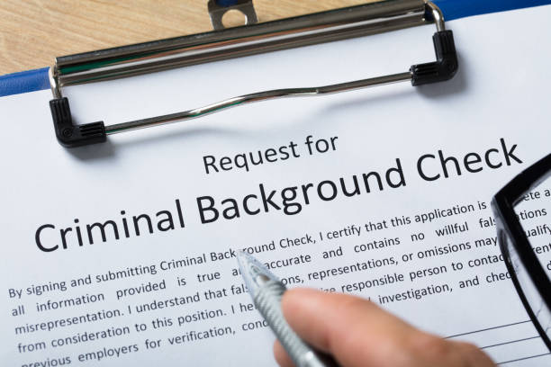 Close-up Of Human Hand Filling Criminal Background Check Application Form With Pen