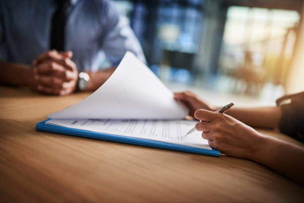 Cropped shot of a man and woman completing paperwork together at a desk Cropped shot of a man and woman completing paperwork together at a desk