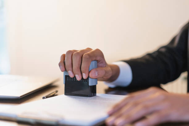 Businessman carefully stamps a document at his desk, showing the world of business and paperwork. His hand in a suit symbolizes precision and control in finance, accounting, and law